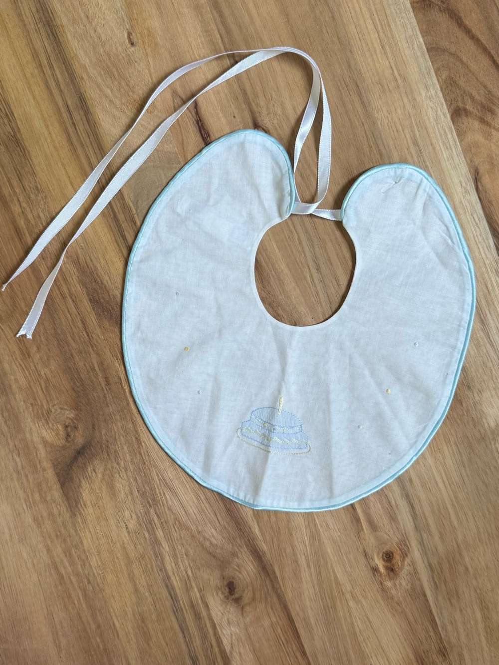 Kissy Kissy White Birthday Cake Bib with Light Blue Trim and Cake Embroidery
